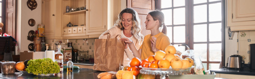 mom and teenage daughter unloading groceries in their gourmet kitchen