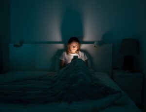 woman in her bed using her phone to look at social media